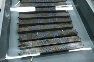 2 Tests were conducted with mortar prisms of the size 25 x 25 x 258 mm. After hardening, the mortar bars were exposed to 1 mol per liter sodium hydroxide (1M NaOH), as shown in the picture. The prisms were completely immersed in the solution and then exposed for 14 days at 80 °C. Dimension changes were checked and measured on a regular basis